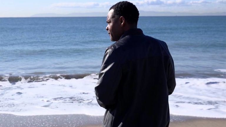 man on a beach looking at the ocean