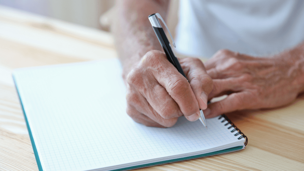 Dementia caretaker writing in a journal to document challenging behaviours