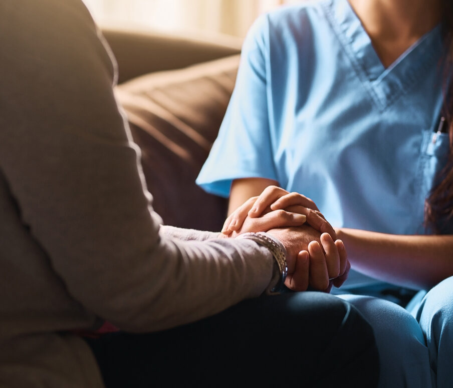 Nurse holding a senior woman's hands in comfort