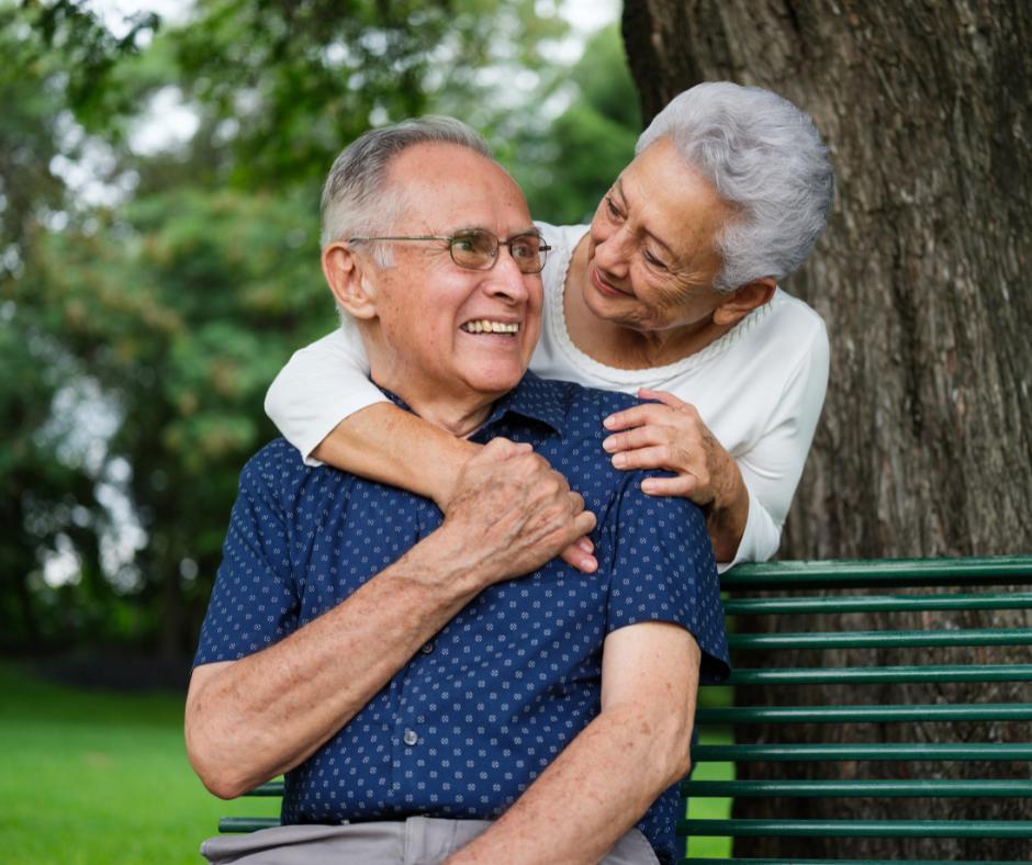 Elderly couple hugging on park bench