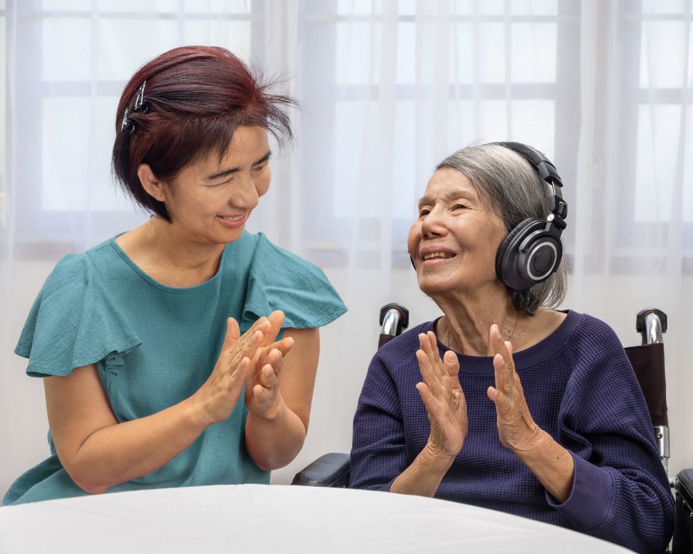 Daughter and senior mother listening to music and clapping hands