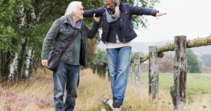 A woman balances on a fence post.