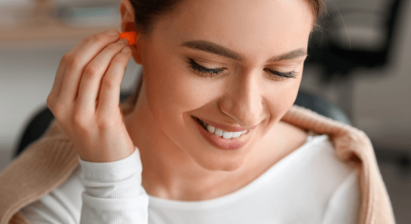 Woman putting in earplugs to help protect her ears, which contributes to brain health.