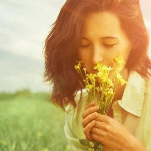 Woman smelling summer flowers from a field