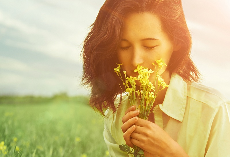 Woman smelling summer flowers from a field