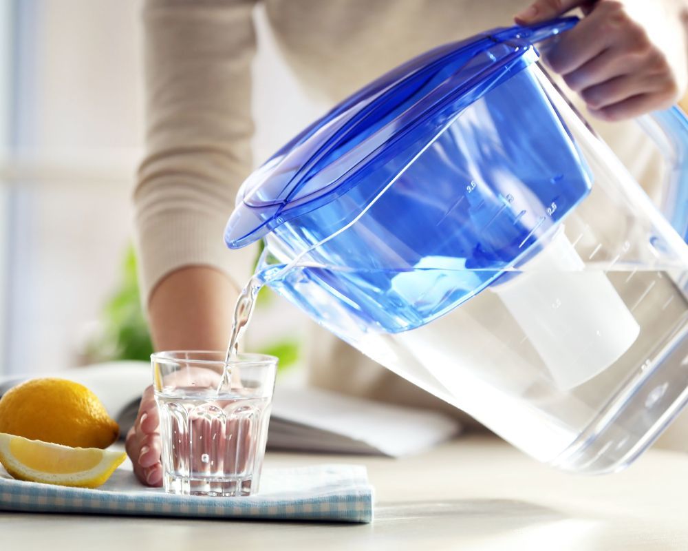Person pouring pitcher of water into a cup