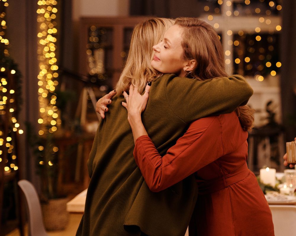 Two women hugging, twinkle lights in the background
