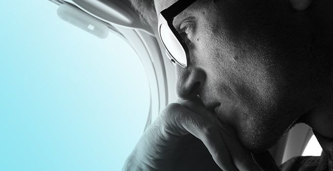 man with glasses looking out an airplane window