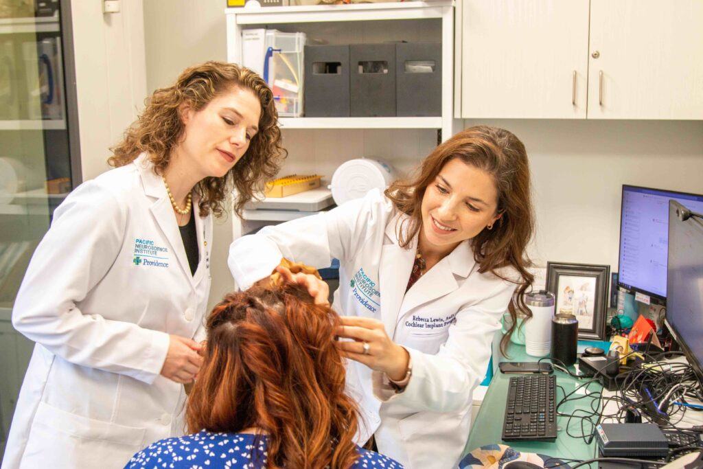 Dr. Lewis and Dr. Voelker examining Ayslyn's Bonebridge implant at the Pacific Neuroscience Institute