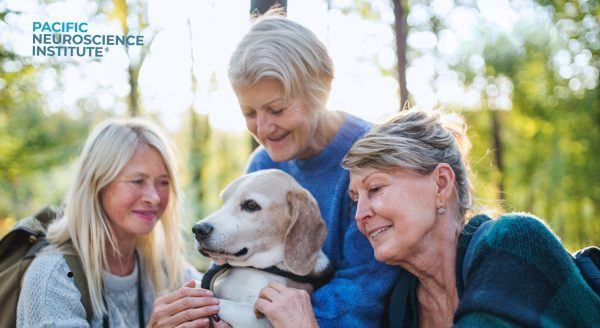 Three senior women outdoors holding a golden lab dog