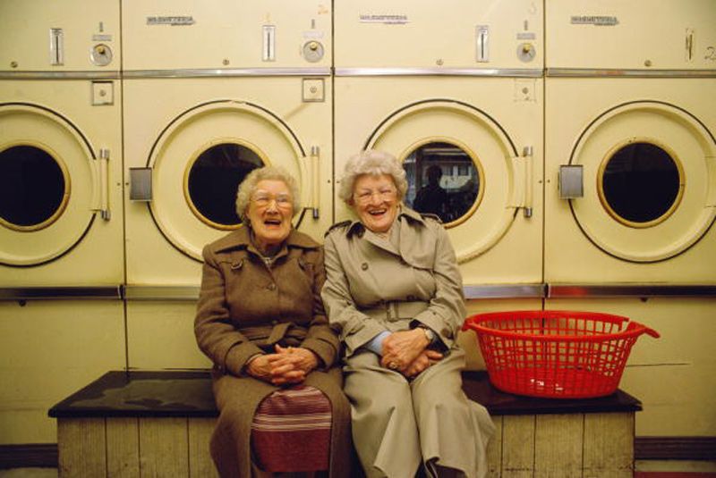 two elderly women sitting in a laundromat