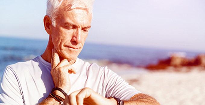 Man standing at the beach and timing his pulse with a watch