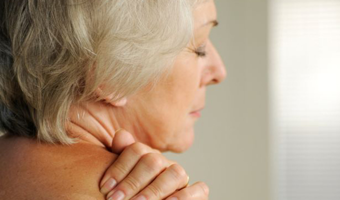 elderly woman holding her shoulder