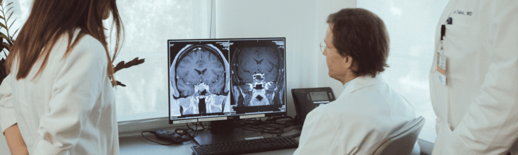 Three doctors reviewing a brain scan on a computer