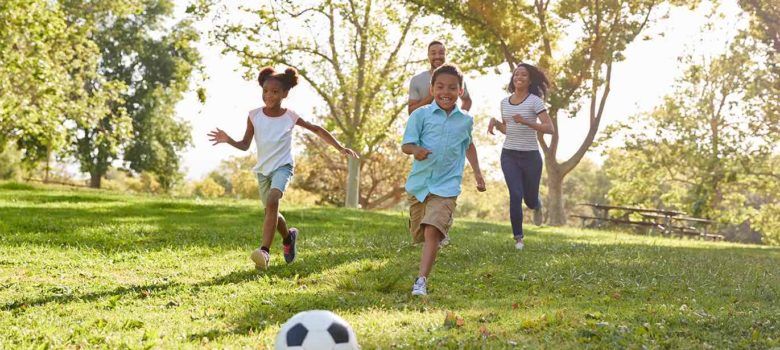 Family playing soccer in the park