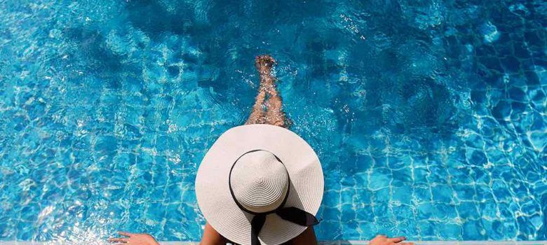 women sitting in a pool with a hat on