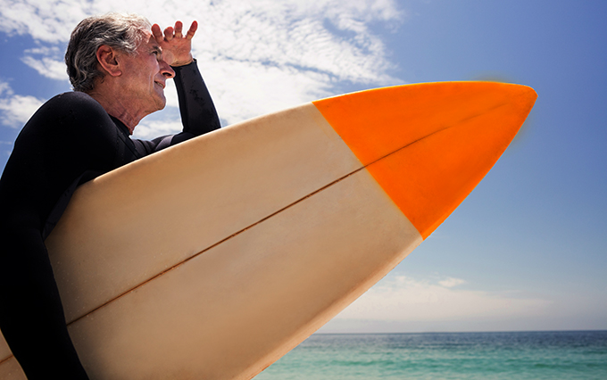 Man holding a surfboard looking out toward the ocean