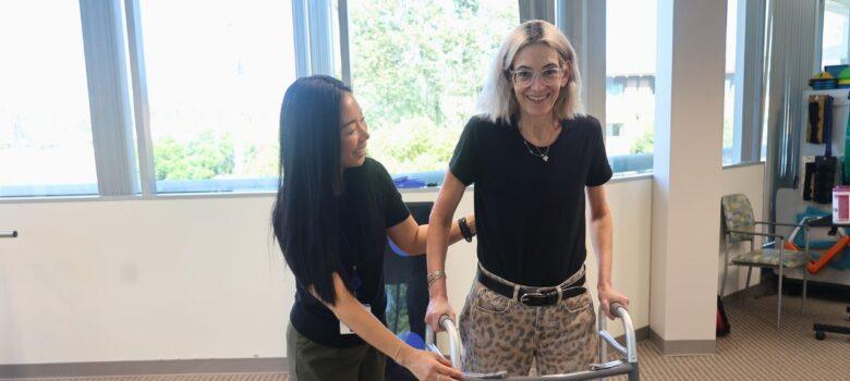Occupational therapist assisting a patient using a walker during rehabilitation.