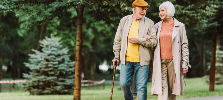 Senior couple smiling while walking on path in park