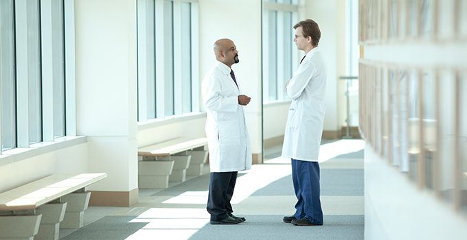 doctors kelly and kesari chatting in a hallway